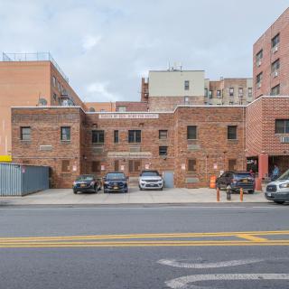 A brick building with parked cars in an urban setting.