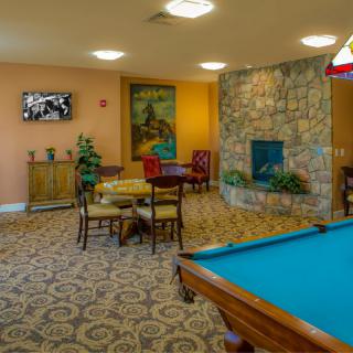 A cozy game room featuring a pool table, seating area, fireplace, and television.