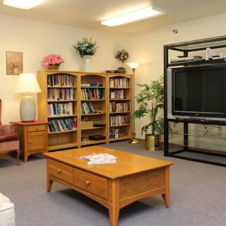 A cozy living room with bookshelves, a large TV, and a wooden coffee table.