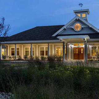 A charming house illuminated at dusk with a welcoming porch and surrounding garden.