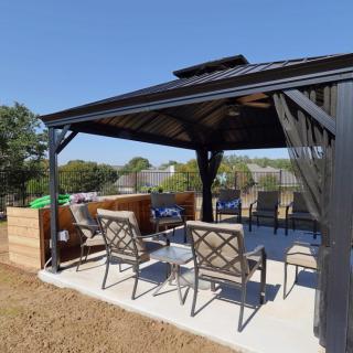 A cozy outdoor seating area under a gazebo in a sunny backyard.