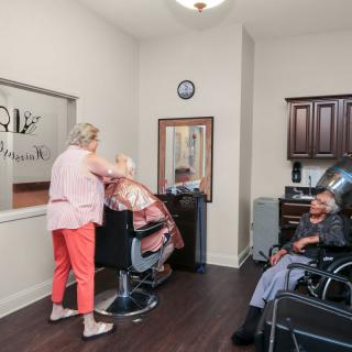 A cozy barber shop with a hairdresser attending to a customer while another person waits.