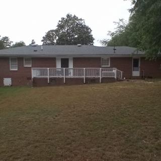 A view of a brick house with a wooden ramp and fence in the backyard.