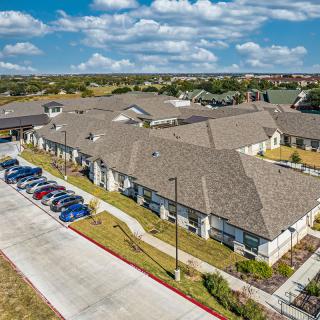 Aerial view of a residential building with a parking lot under a cloudy sky.