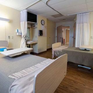 An empty hospital room with two beds and curtains for privacy.