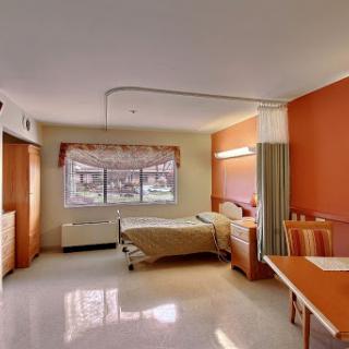A bright and clean hospital room equipped with a bed, table, and window.
