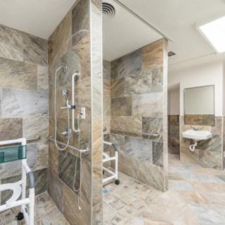 A modern, accessible bathroom with a walk-in shower and stone tile design.