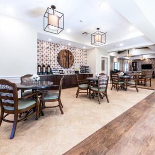 A spacious and elegantly designed dining area with wooden tables and chairs, featuring a coffee station and stylish lighting.