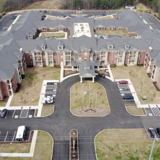 Aerial view of a large residential building with a surrounding parking lot.