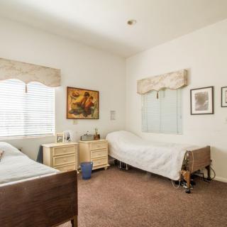 A cozy bedroom with two single beds, nightstands, and decorative paintings on the walls.