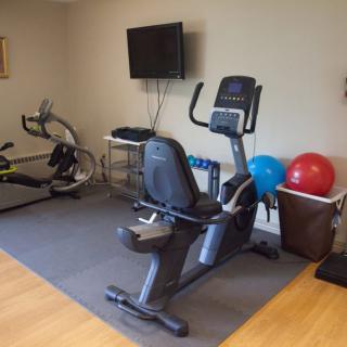A home gym setup featuring a stationary bike, exercise balls, and a television.