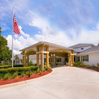 A building entrance with an American flag and landscaped surroundings under a partly cloudy sky.
