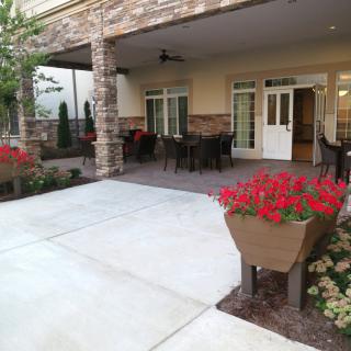 A cozy patio with outdoor seating and vibrant flowers in front of a building.