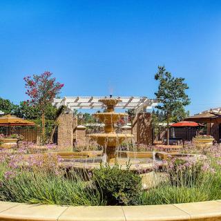 A beautiful garden with a central fountain under a clear blue sky.