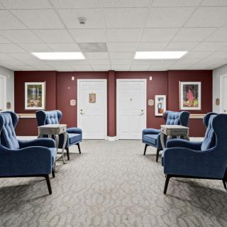 A modern lounge area with blue armchairs and framed artwork on the walls.