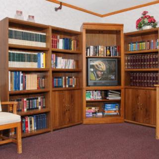 A cozy library corner with wooden bookshelves, a television, and a chair.