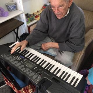 An elderly person playing a keyboard indoors.