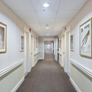 A well-lit hallway with doors and framed artwork on the walls.