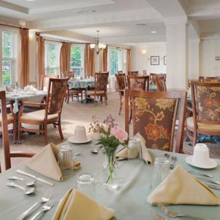An elegantly set dining room with multiple tables and chairs, ready for guests.
