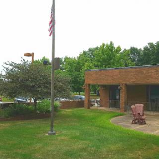 A serene view of a brick building with an American flag and green surroundings.