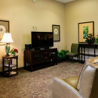 A cozy living room with a television, artwork, and comfortable seating.