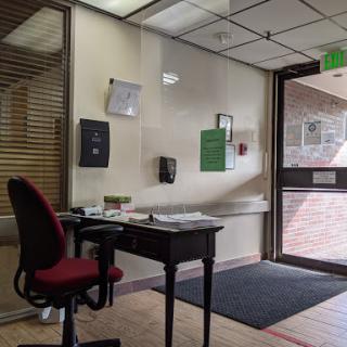 A view of an office reception area featuring a desk and chair, with an entrance door visible.