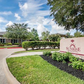 A scenic view of a building with well-maintained landscaping and a prominent entrance sign on a sunny day.