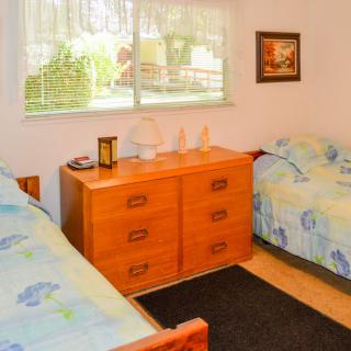 A cozy bedroom with twin beds, a wooden dresser, and a window overlooking the garden.