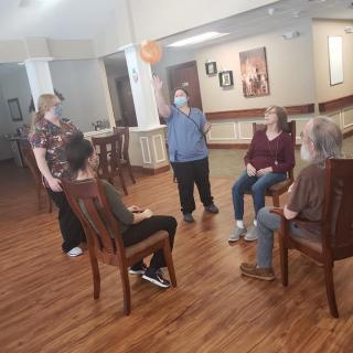 A group of people engaging in a seated activity inside a community room.