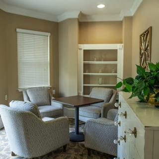 A cozy living room corner with comfortable chairs, a small table, and a bookshelf.