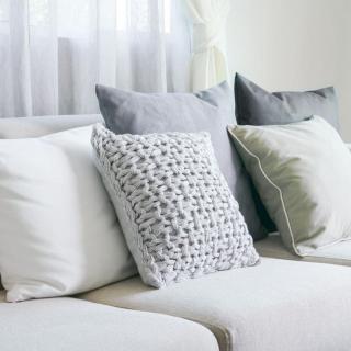 A cozy sofa adorned with a variety of pillows and cushions in neutral tones, enhancing the living room's interior design.