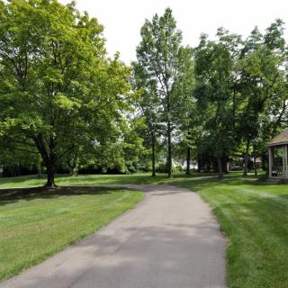 A serene pathway meandering through a lush park with abundant trees and greenery.