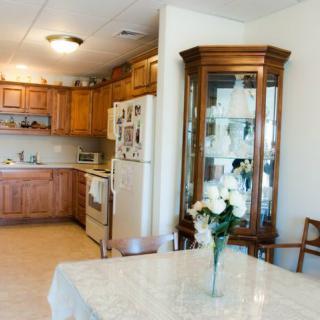 A cozy kitchen and dining area with wooden cabinets and a china cabinet, featuring a table adorned with a vase of flowers.