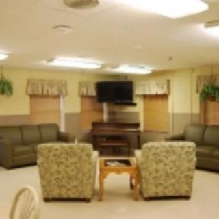 A cozy living room with sofas, armchairs, a coffee table, and a wall-mounted television.