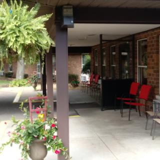 A welcoming entrance with red chairs and hanging plants, creating a cozy outdoor atmosphere.