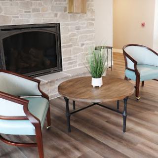 A cozy living room setup featuring elegant chairs and a rustic coffee table by the fireplace.