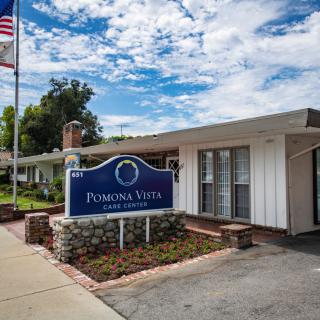 Exterior view of Pomona Vista Care Center with a sign and flag.