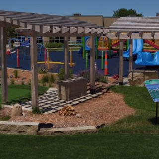 A vibrant outdoor playground featuring colorful structures, green lawns, and shaded seating areas.