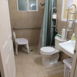 An accessible bathroom with a toilet, sink, and shower area equipped with a curtain and grab bar.