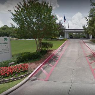 A landscaped driveway with a gated entrance and signage.