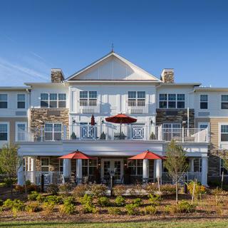 A modern residential building with outdoor seating and landscaped gardens.