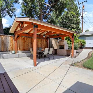 A backyard patio with a wooden pergola and outdoor seating.