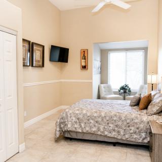 A cozy bedroom featuring a bed, television, and window seating area.