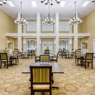 A spacious and modern dining area with multiple tables and elegant chandeliers.
