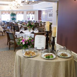 An elegant dining area with a food display table at the entrance, set for guests.