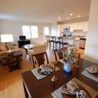 A modern open concept living space featuring a cozy living room, dining area, and kitchen with hardwood floors and elegant decor.