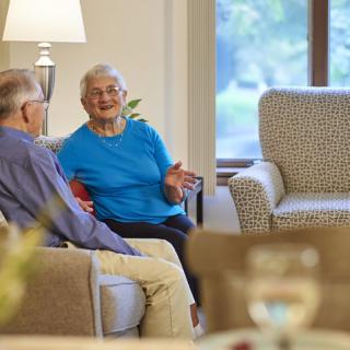 Two seniors enjoying a conversation in a cozy living room setting.