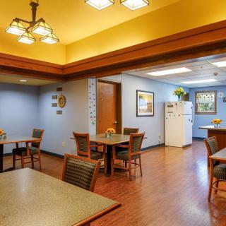 A cozy dining area with tables and chairs adjacent to a kitchen space.