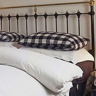 A neatly made bed with checkered pillows and a metal headboard.