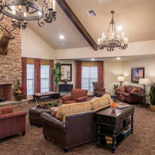 A cozy living room featuring a stone fireplace, comfortable seating, and elegant chandeliers.